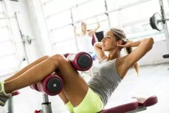 Young woman exercise abs in the gym on the bench